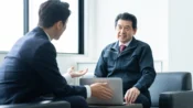 パソコンを囲んで話し合う経営者と社員